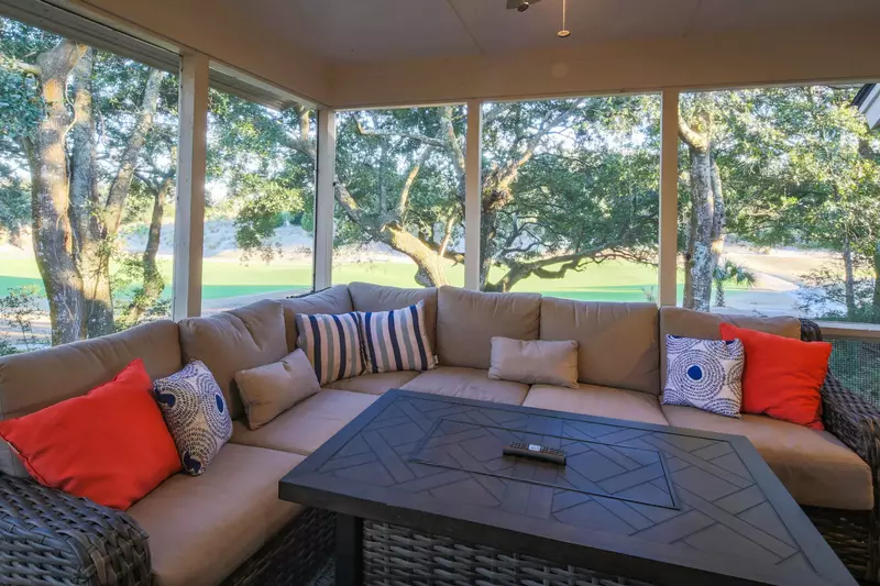 The screened porch features a spacious sectional, ceiling fan and peaceful views of the golf course.