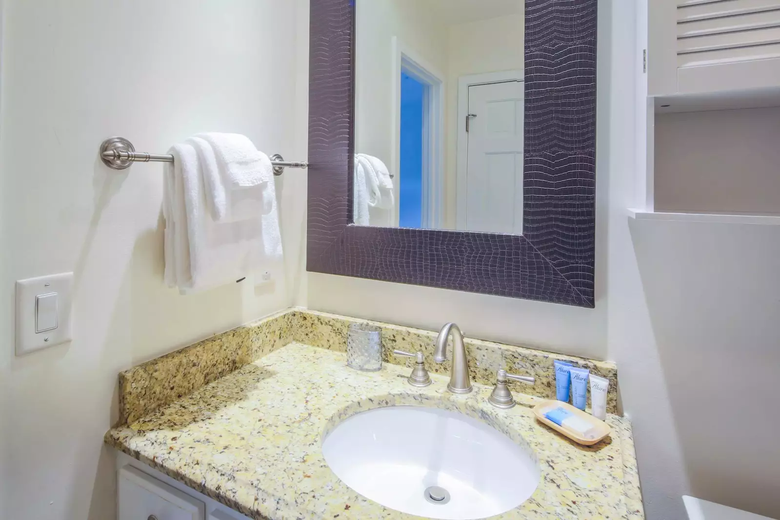 This en suite bathroom features a spacious vanity with granite countertops.