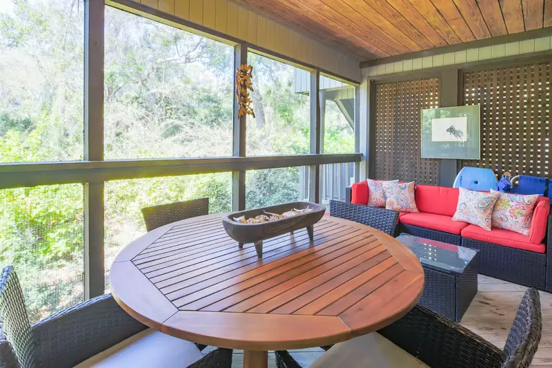 The screened porch features an outdoor dining table and a comfortable sectional.