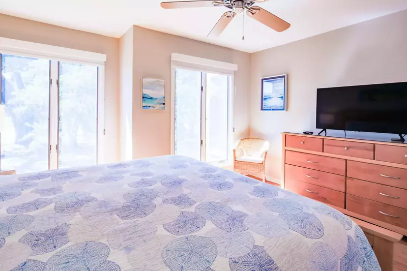 The master suite also has a dresser, chair, ceiling fan and streaming TV.
