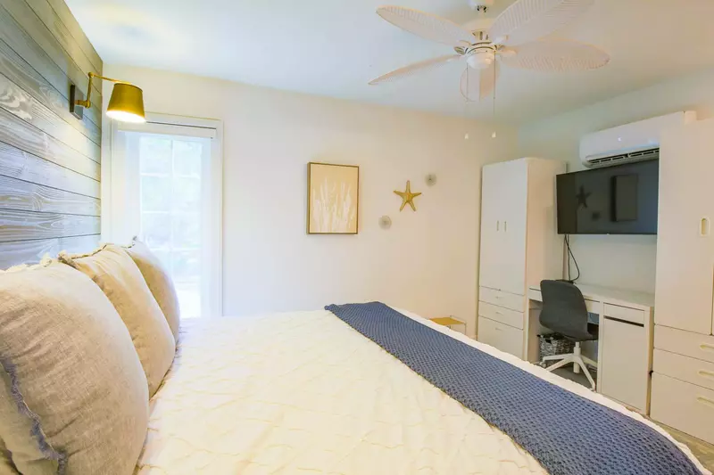 The living room also has armoires, a desk and mounted smart TV.