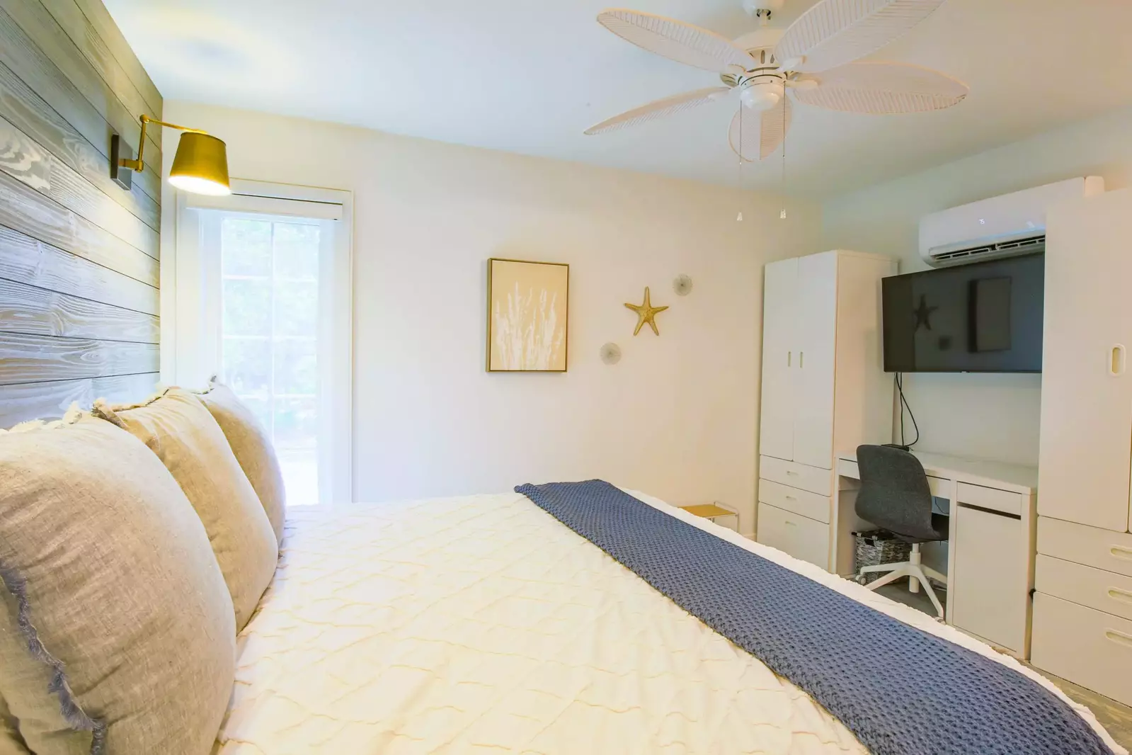 The living room also has armoires, a desk and mounted smart TV.