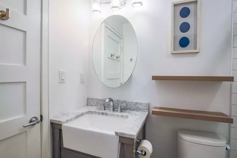 The renovated bathroom features a modern vanity and floating shelves.