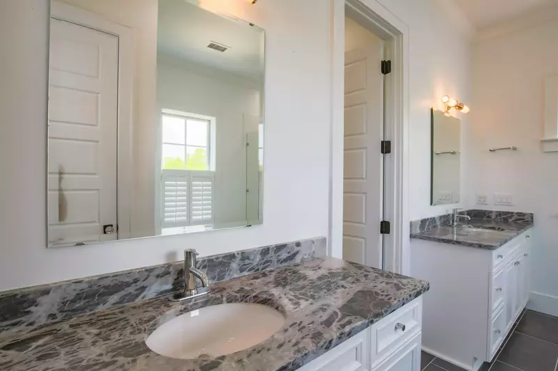 This en suite bathroom features dual vanities with granite counters and tiled flooring.