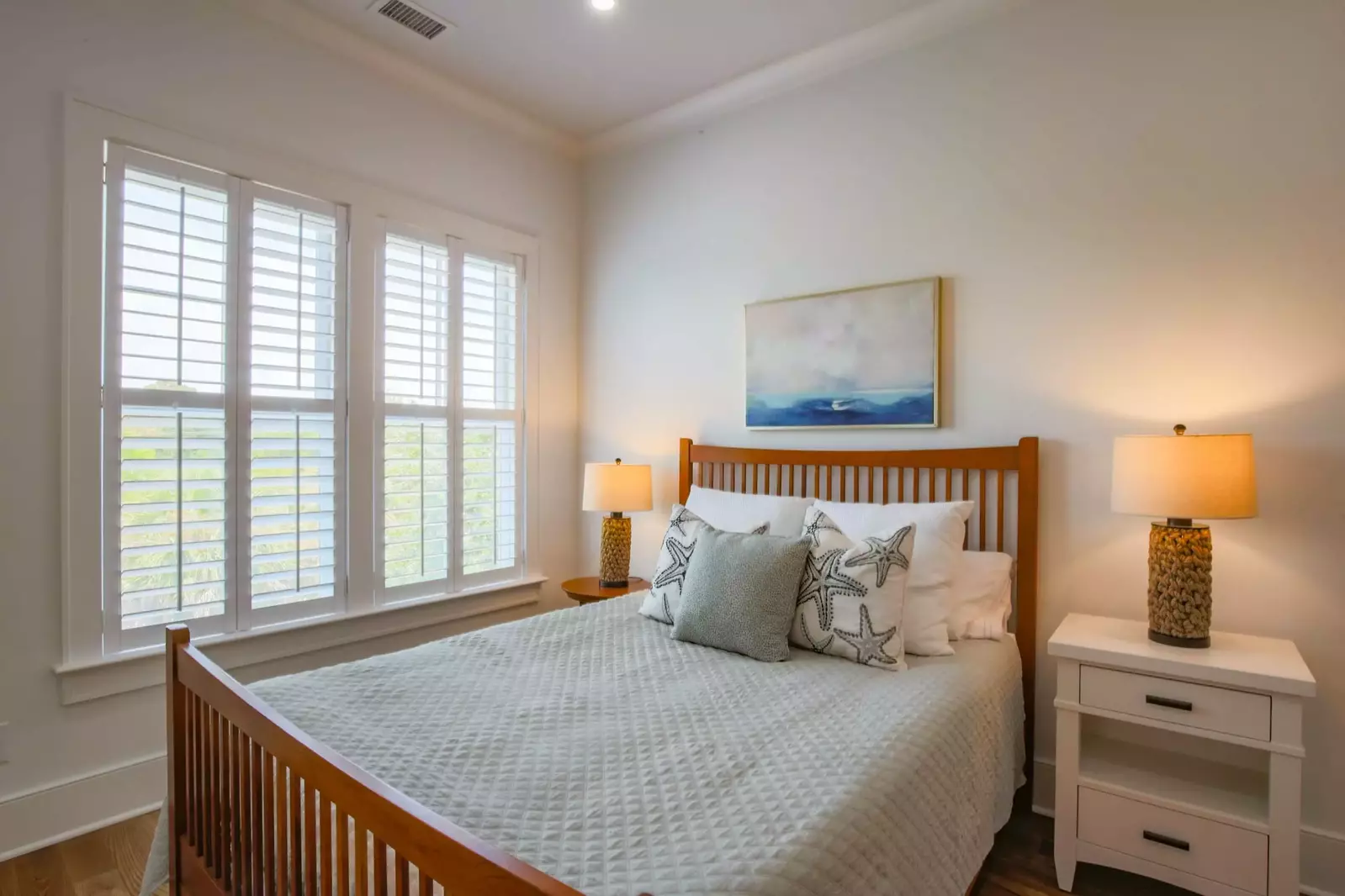 This guest bedroom, located on the home's upper level, features a queen bed and night stands with reading lamps.