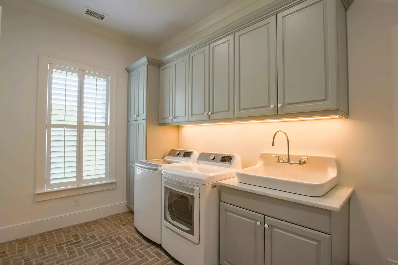 Even the laundry room is spacious and gorgeous with its brick flooring, large utility sink and custom cabinetry.