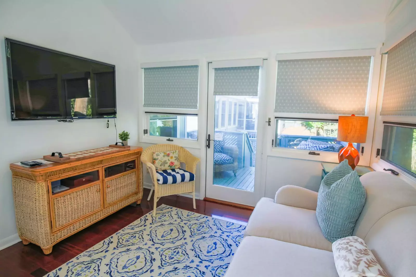 The sunroom has a wall-mounted smart TV and access to the back porch.