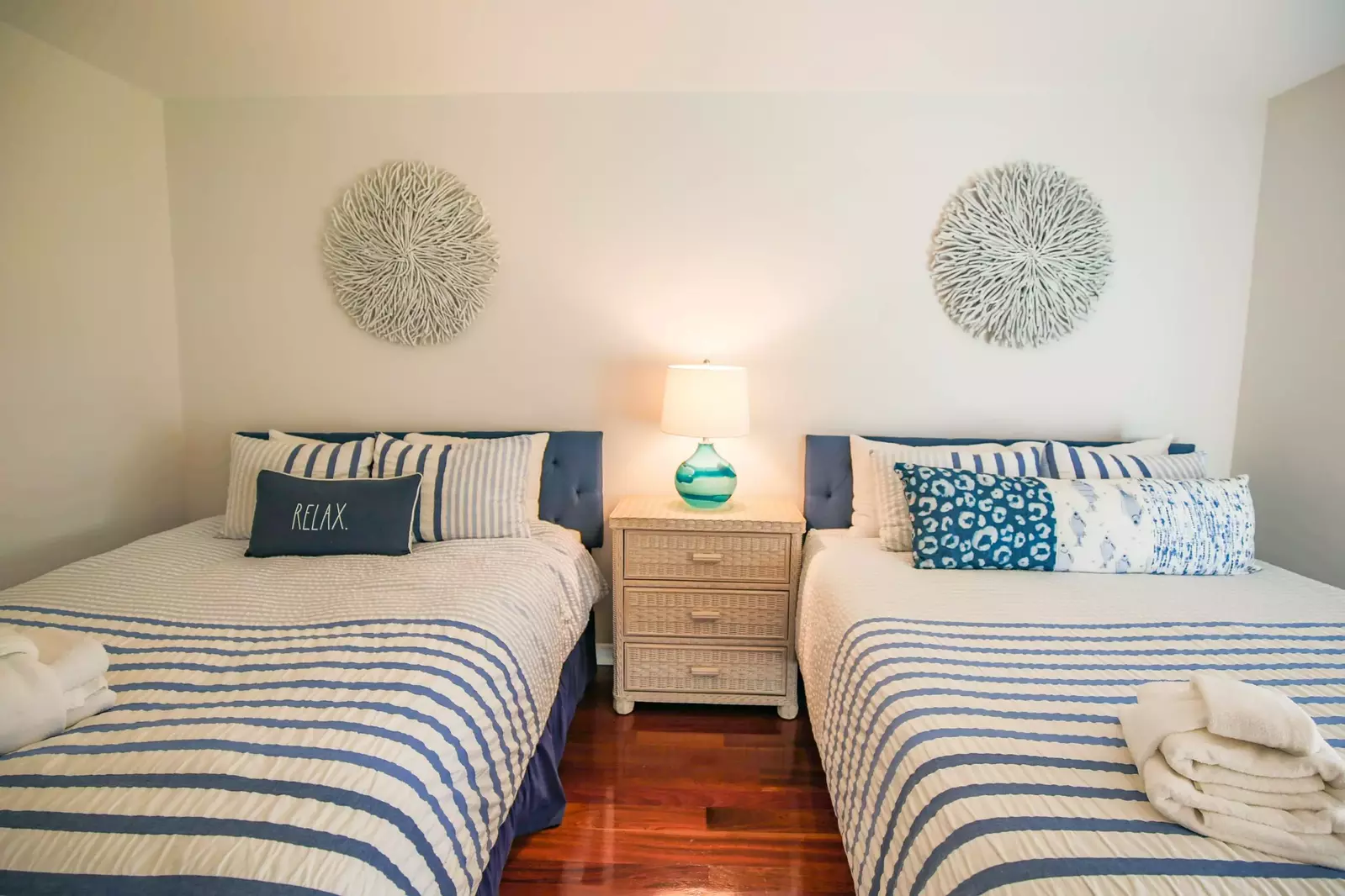 This guest bedroom features two queen beds and a night stand with a reading lamp.