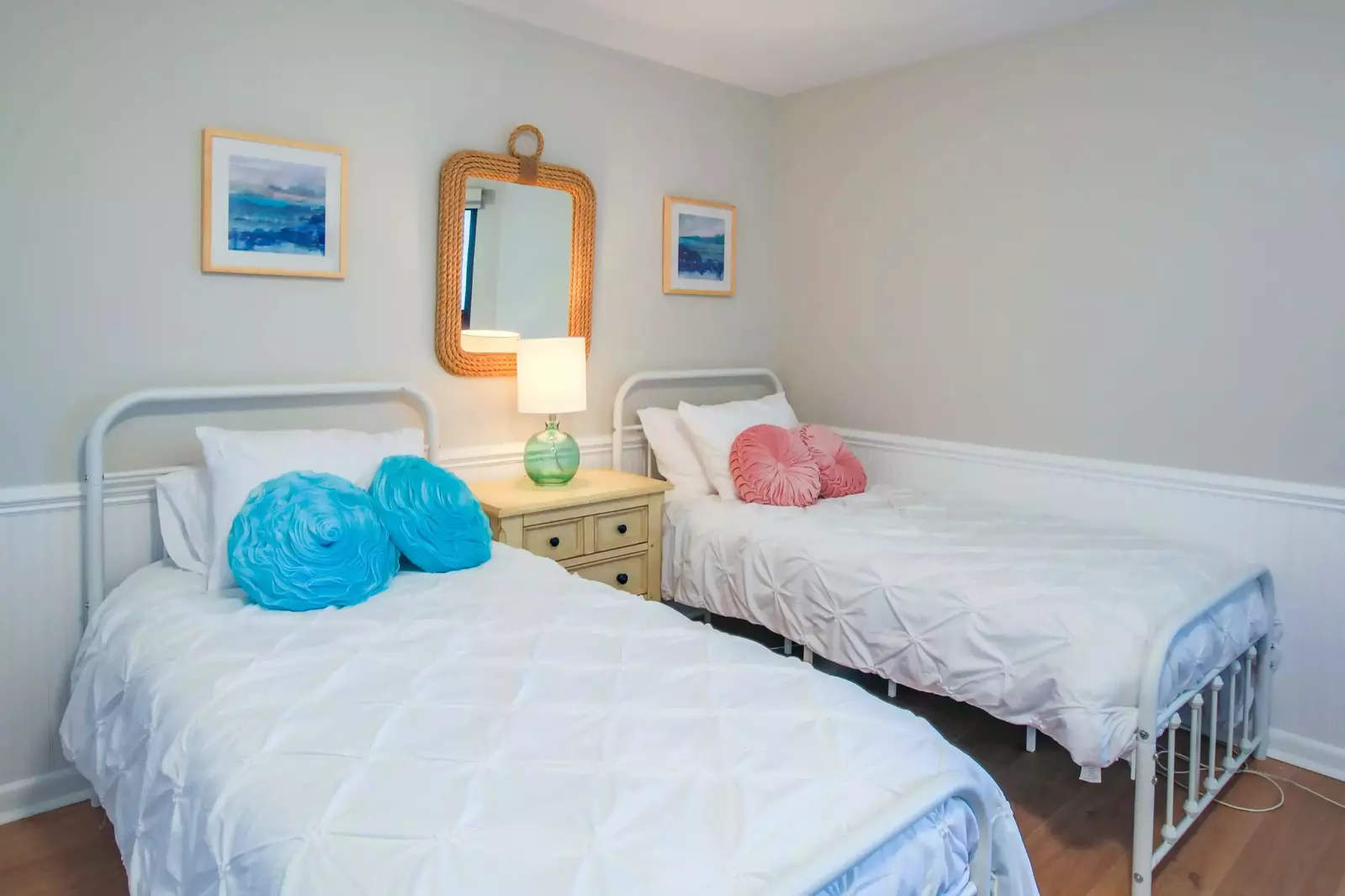 The guest bedroom features two twin beds and a night stand with a reading lamp.