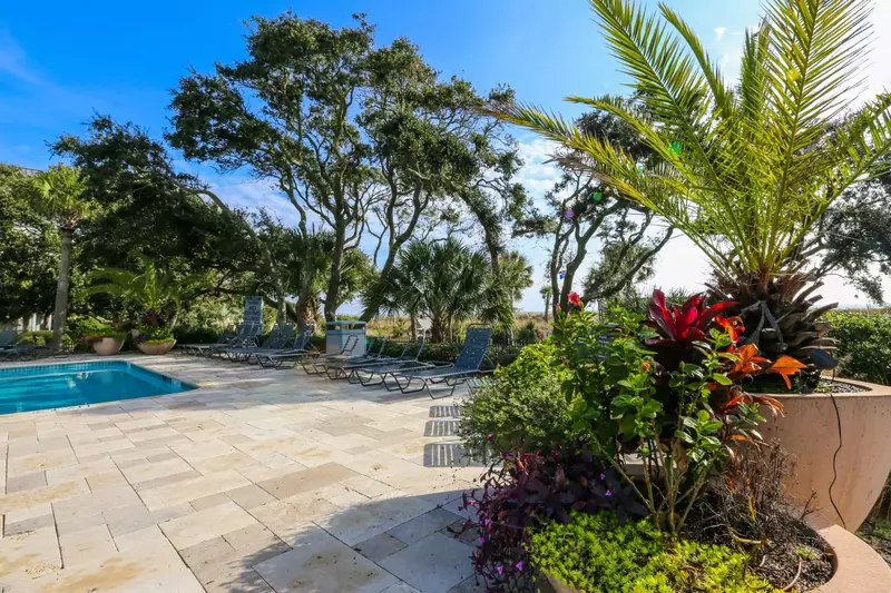 The community pool features a large sundeck with loungers and potted plants.