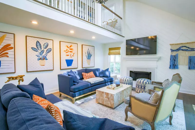 The living room has a wall-mounted smart TV and views of the second floor balcony.