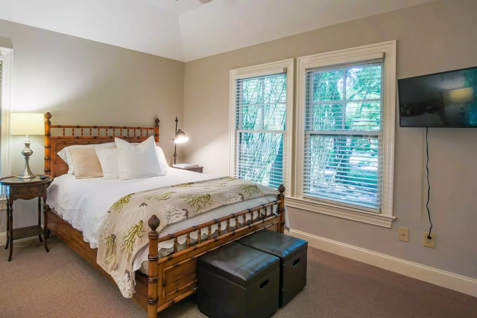 This bedroom features a queen bed, night stands with reading lamps and a smart TV.