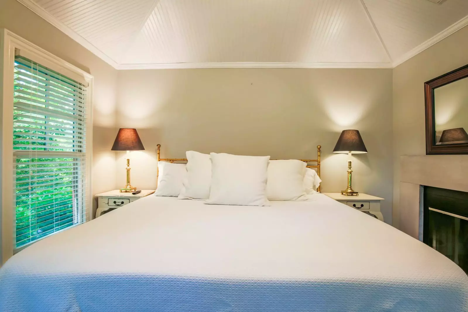 The king bed is flanked with two night stands with reading lamps.  (Fireplace not available for guest use.)