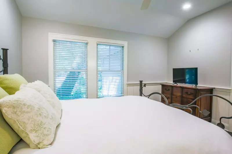 This guest bedroom features a dresser with smart TV and access to a bathroom.