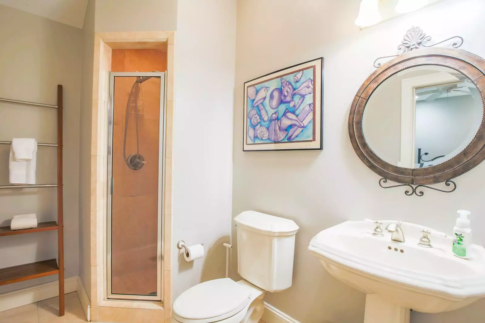 This bathroom features a pedestal sink and a tiled, walk-in shower.