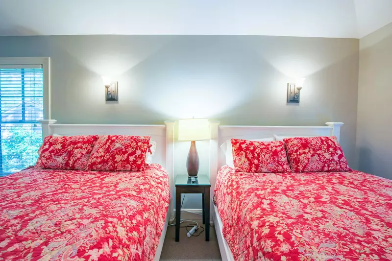 This bedroom has a night stand with a reading lamp and two sconces.