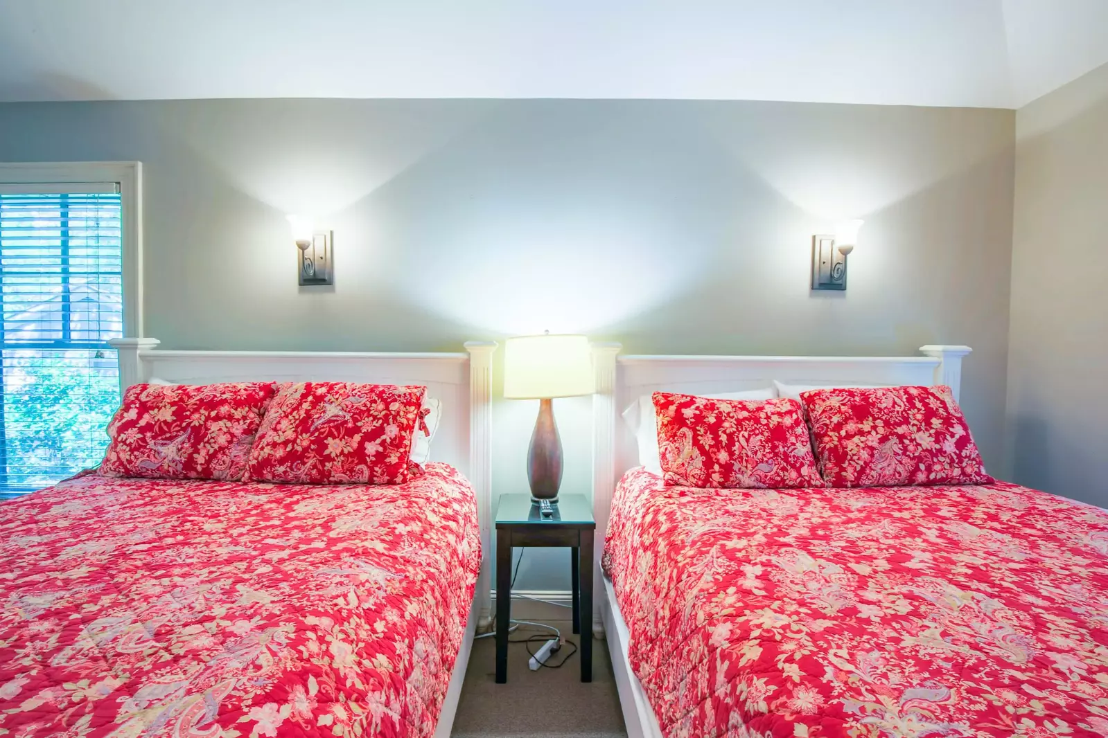 This bedroom has a night stand with a reading lamp and two sconces.