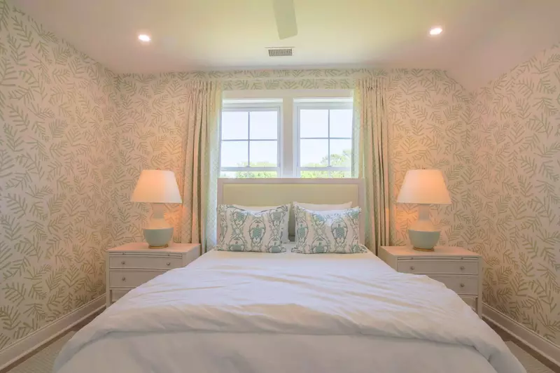This guest bedroom features a queen bed and night stands with reading lamps.