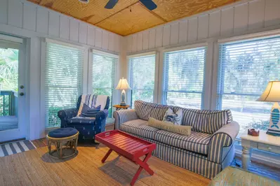 The sunroom has a comfy seating area, lovely natural light and an access point to the back porch.