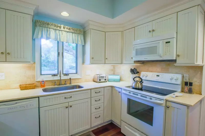 The kitchen features white appliances and white cabinets.