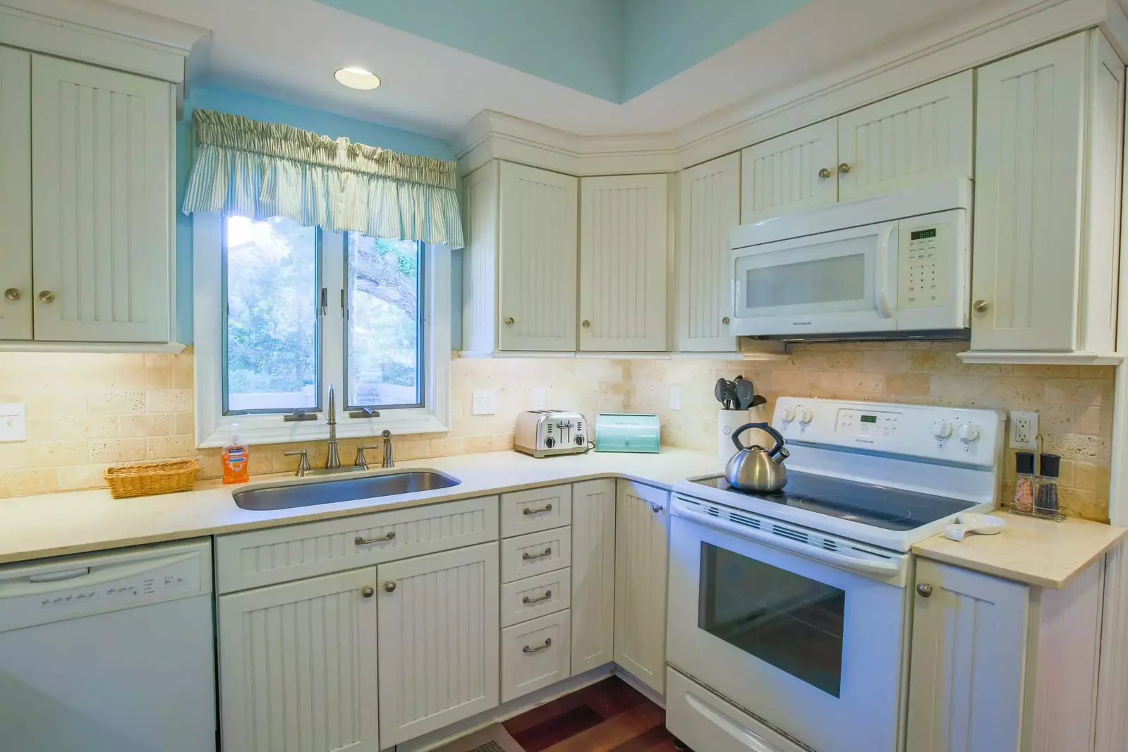 The kitchen features white appliances and white cabinets.
