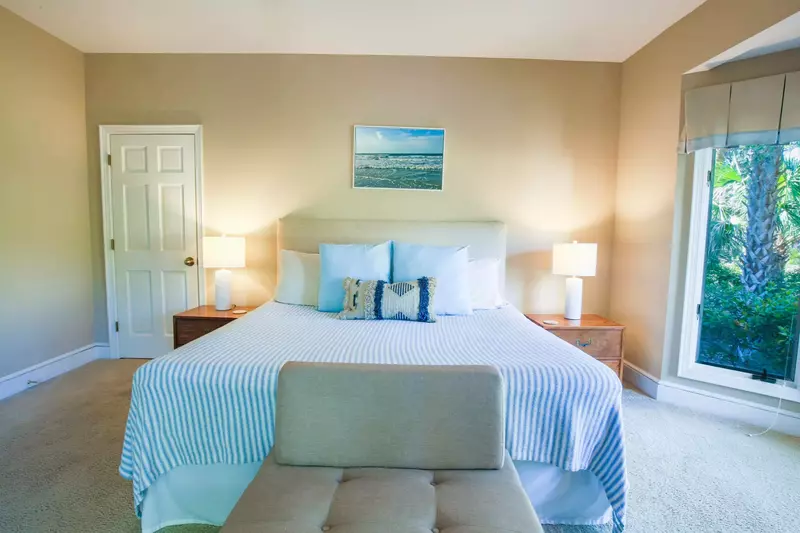 There are two night stands with reading lamps and a small bench near the king bed.