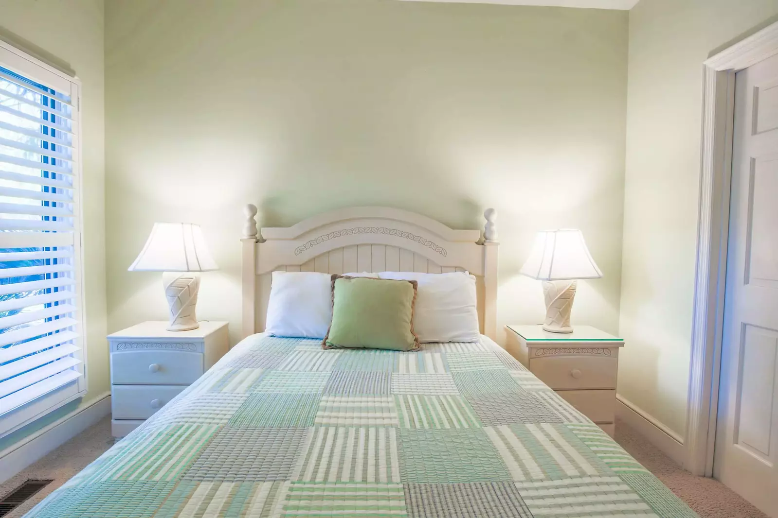 This guest bedroom features a queen bed and night stands with reading lamps.