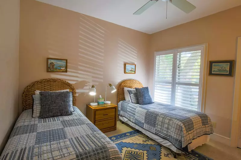 This guest bedroom features two twin beds and a night stand with reading lamps.
