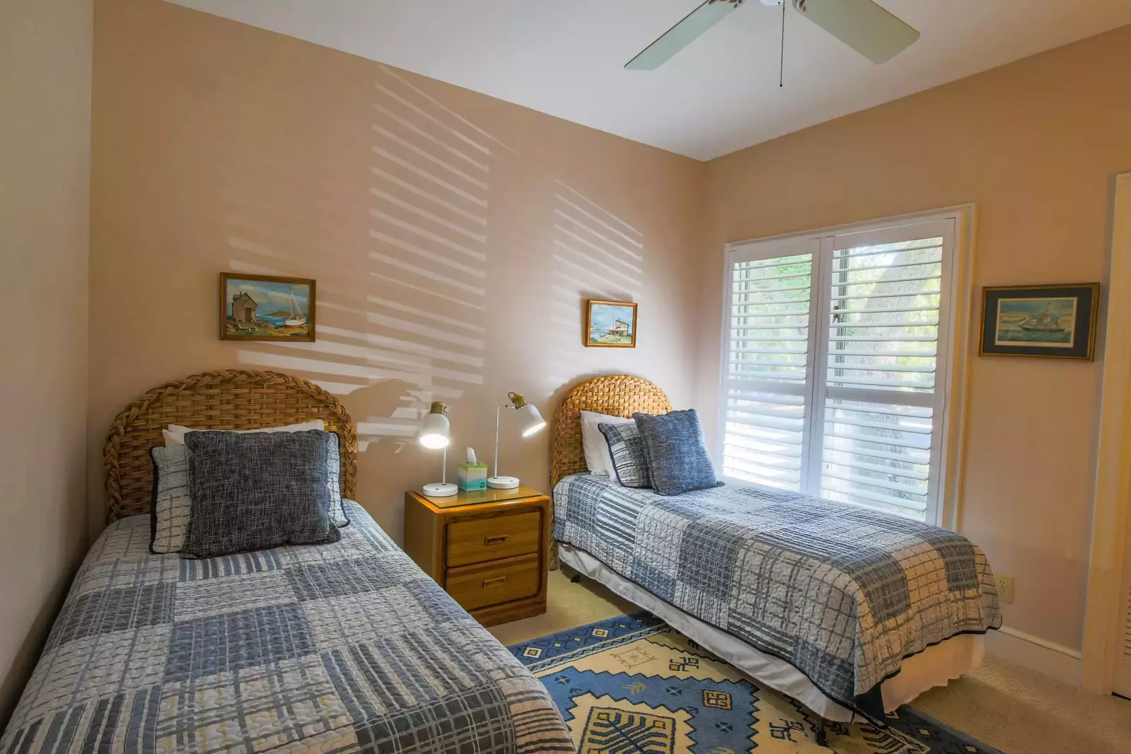 This guest bedroom features two twin beds and a night stand with reading lamps.