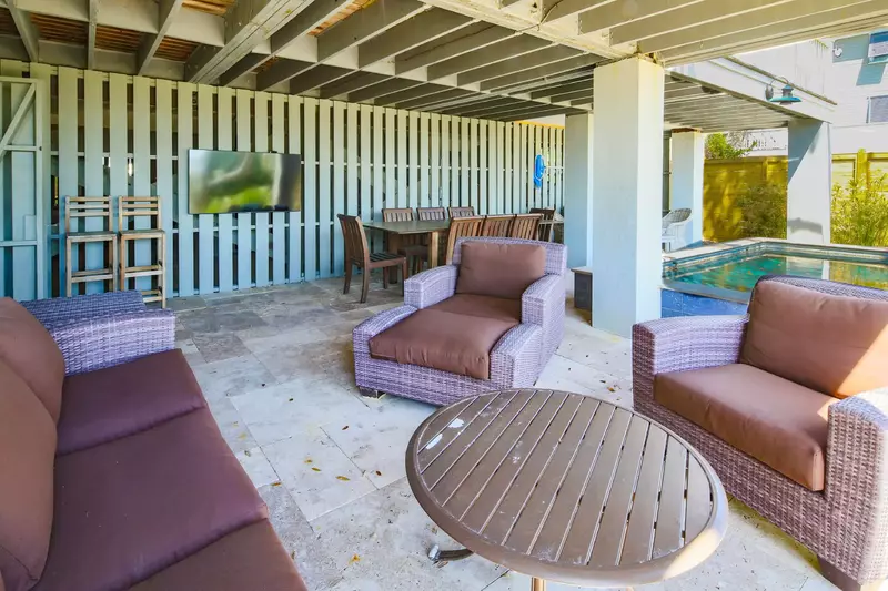 There is an outdoor dining table, wall-mounted TV and cushioned seating area on the patio.