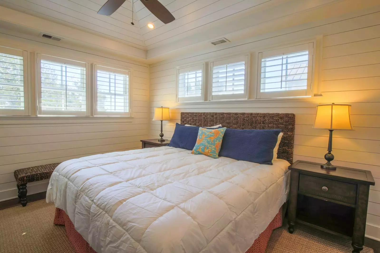 The master suite, located on the 2nd floor, has shiplap walls, a king bed and night stands with reading lamps.