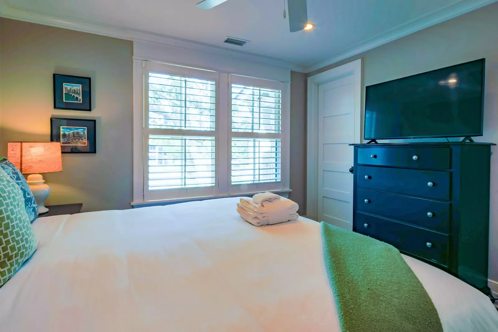 This guest suite features a king bed, night stands with reading lamps and dresser with TV.