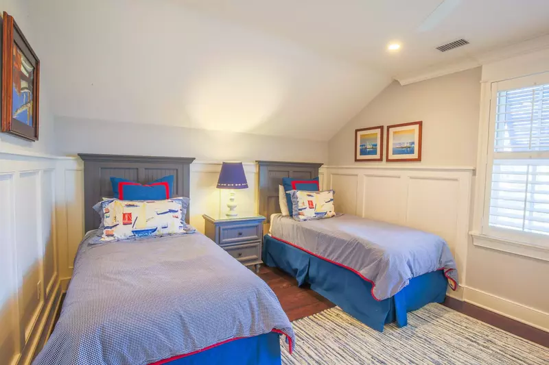 This upper level bedroom features two twin beds and a night stand with a reading lamp.
