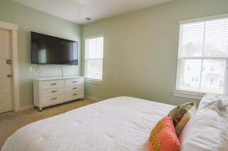 The master bedroom also features a dresser, wall mounted streaming TV and an en suite bathroom.