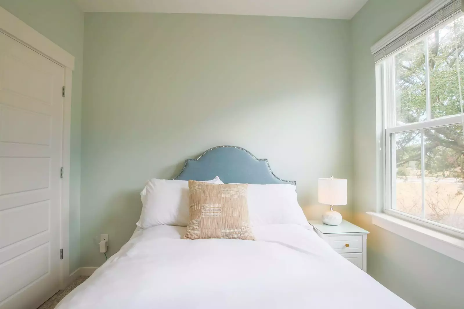 This guest bedroom features a full bed and a night stand with a reading lamp.