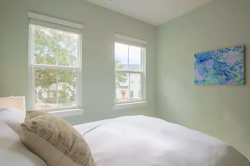 This guest bedroom receives lovely natural light through the two front windows.