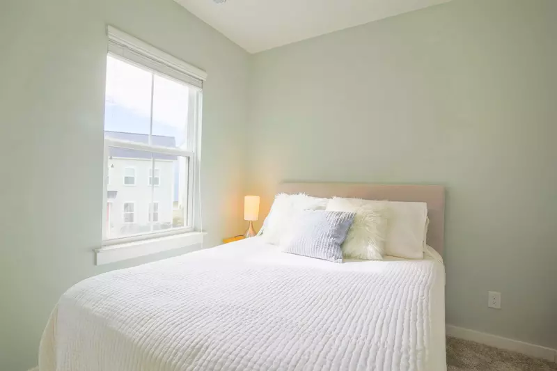 This guest bedroom features a queen bed and a night stand with a reading lamp.