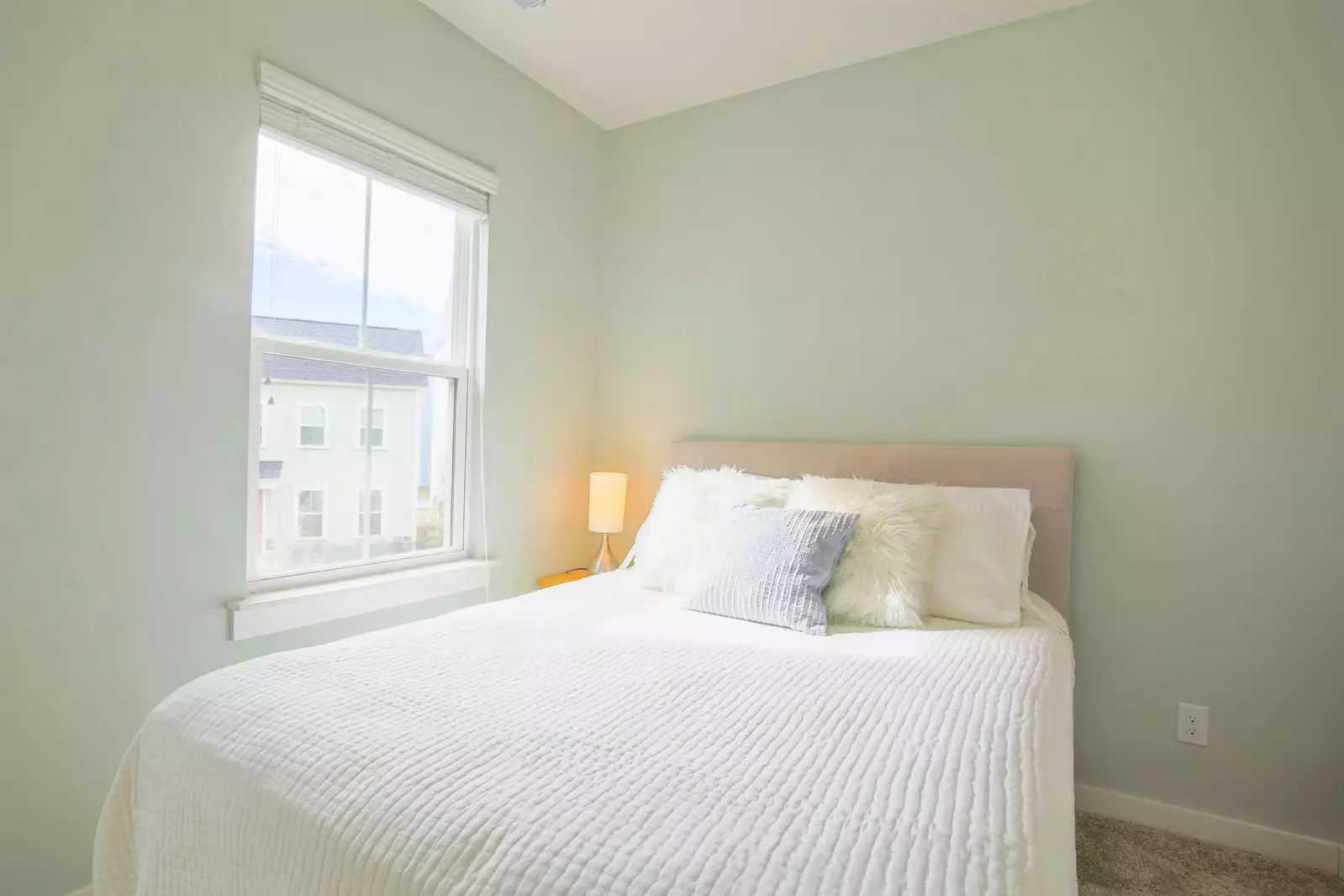 This guest bedroom features a queen bed and a night stand with a reading lamp.