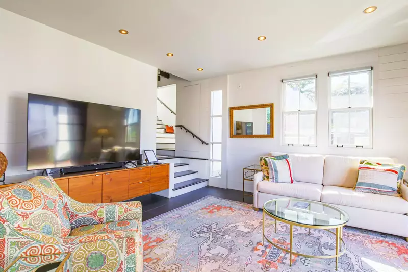 The stairs within the living room lead to the kitchen and the staircase to the home's two master suites.