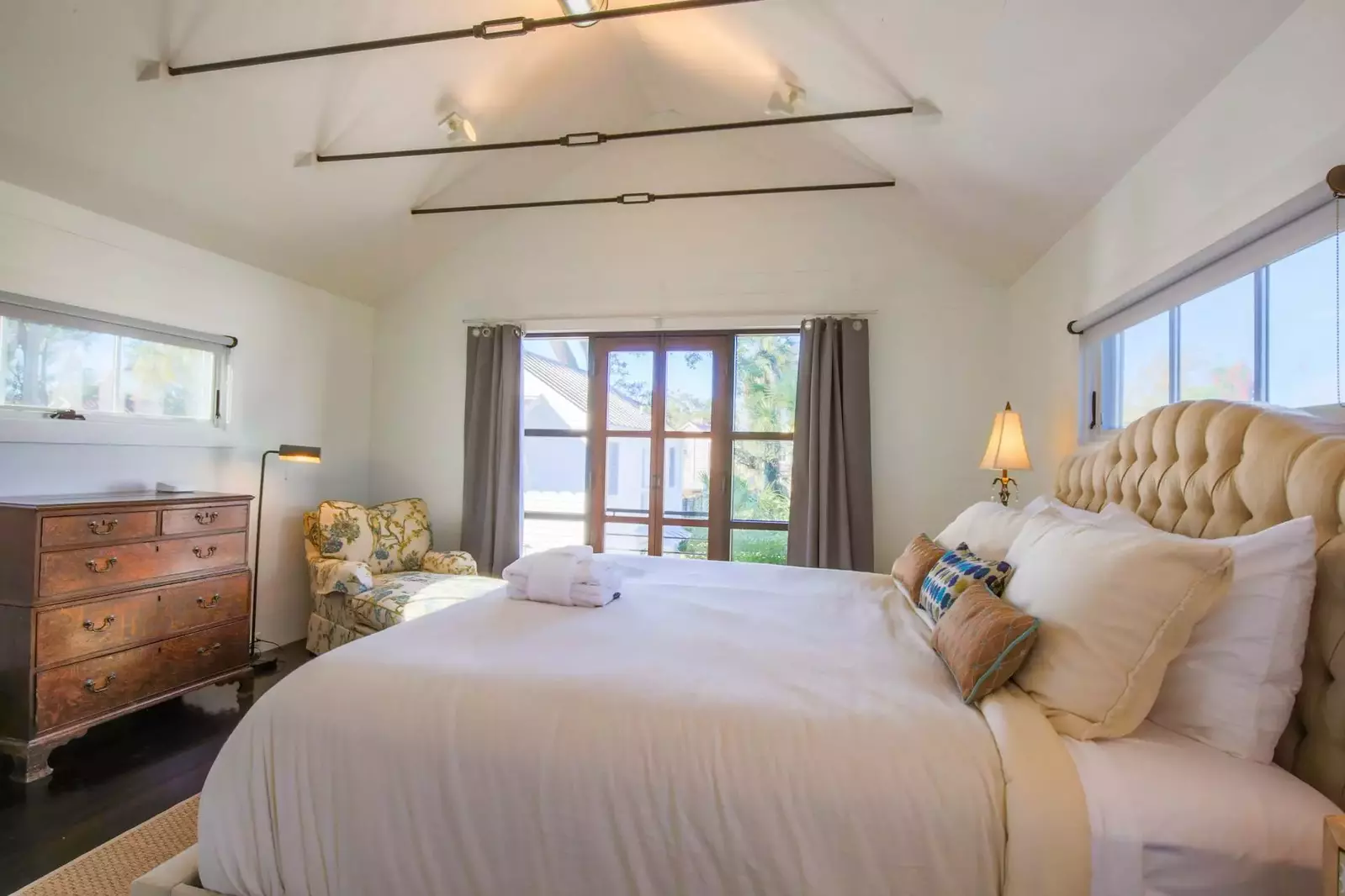 This master suite features a king bed, dresser and chaise arm chair.
