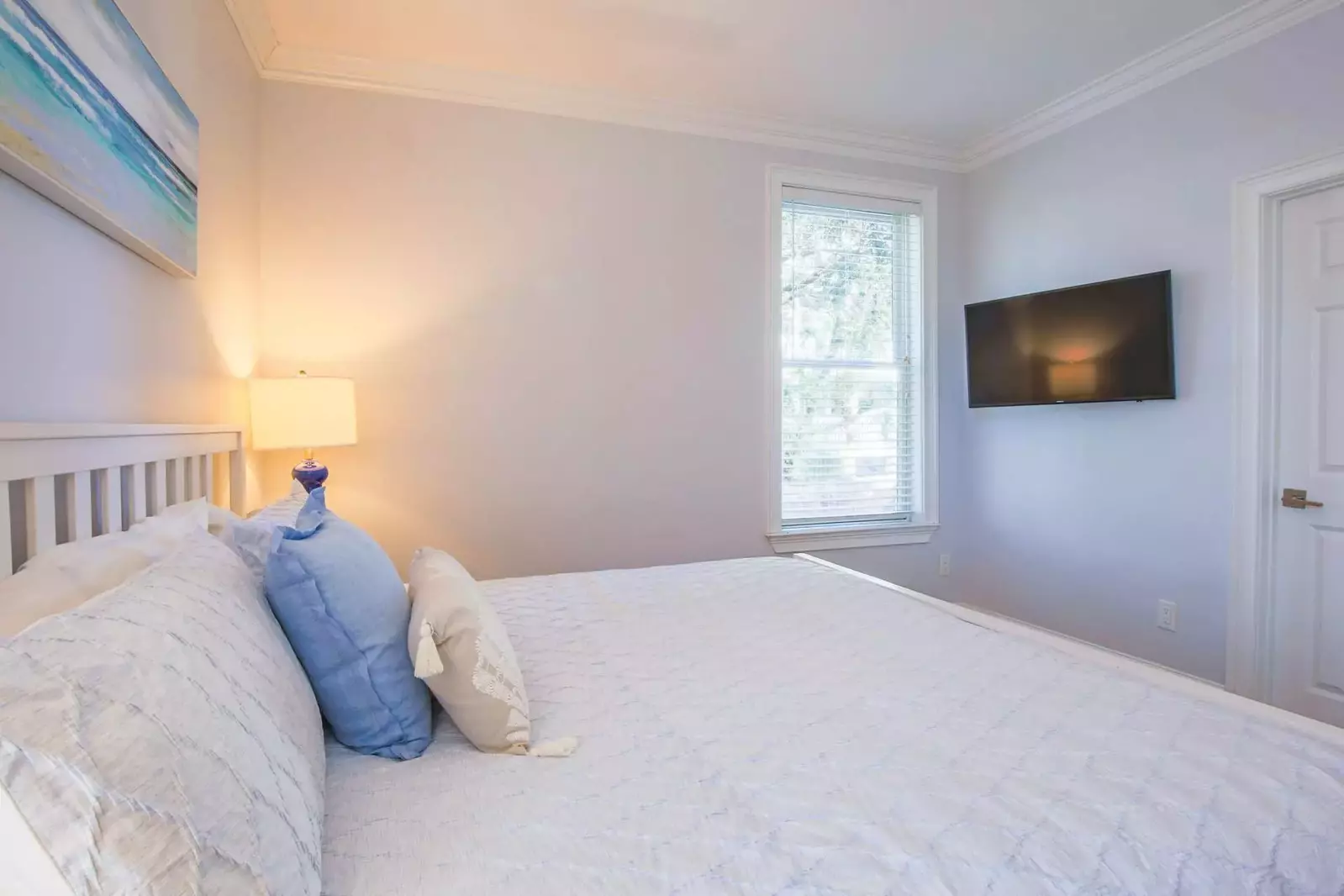 This guest bedroom has a mounted, smart TV and access to a bathroom.