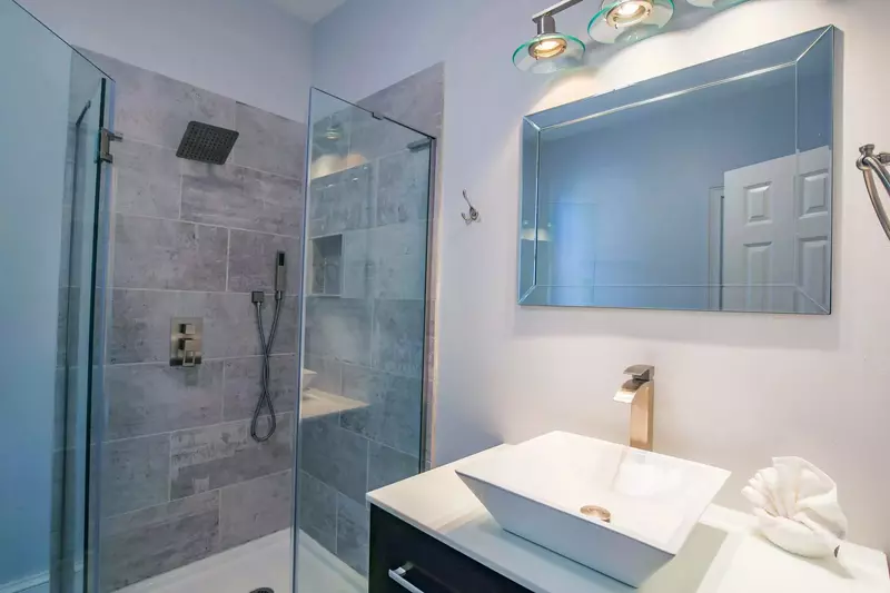 This bathroom features a tiled, walk-in shower and a vanity.