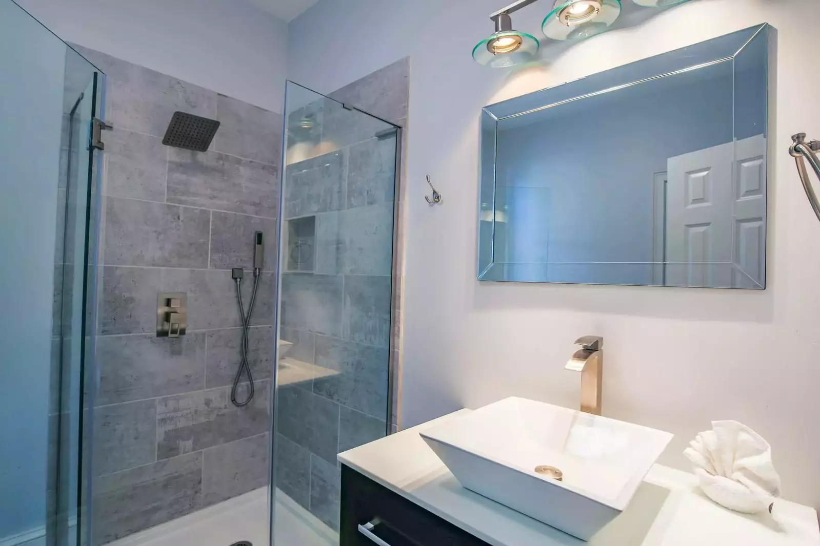 This bathroom features a tiled, walk-in shower and a vanity.