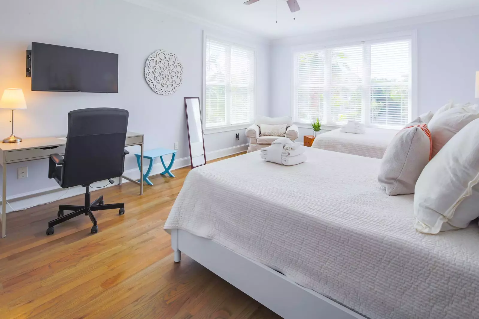 This guest bedroom has a desk, arm chair and wall-mounted streaming TV.