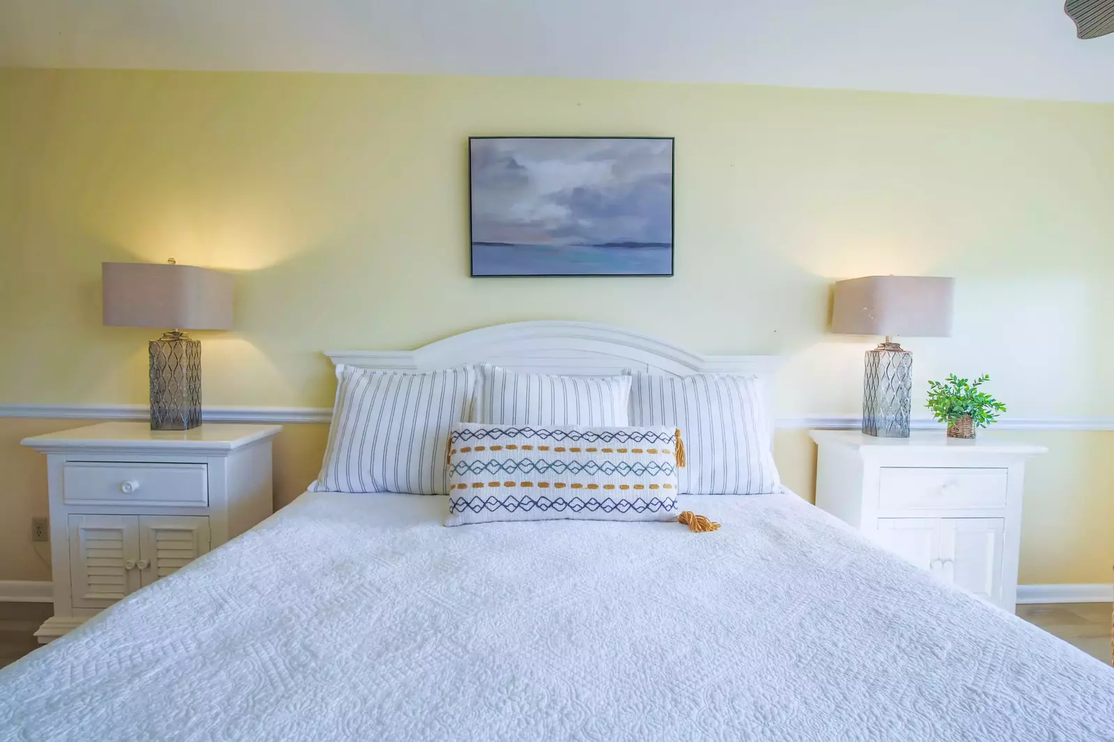 There is a night stand with a reading lamp on each side of the king bed.