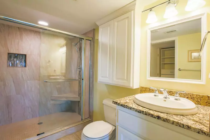The en suite bathroom for the master bedroom features a tiled walk-in shower, vanity and closet.