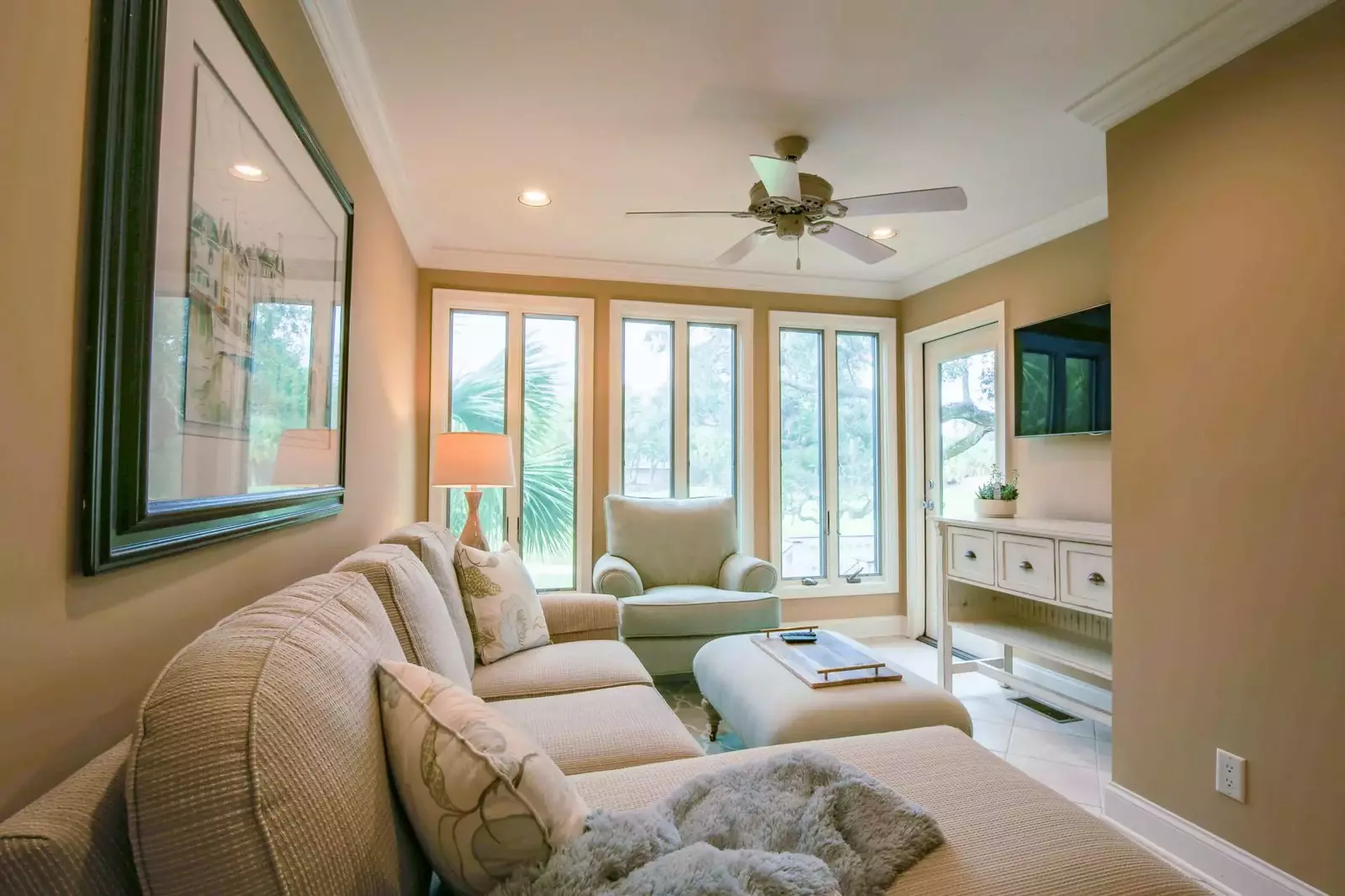 This seating area features a sectional sofa, arm chair, mounted smart TV and door to the back deck.