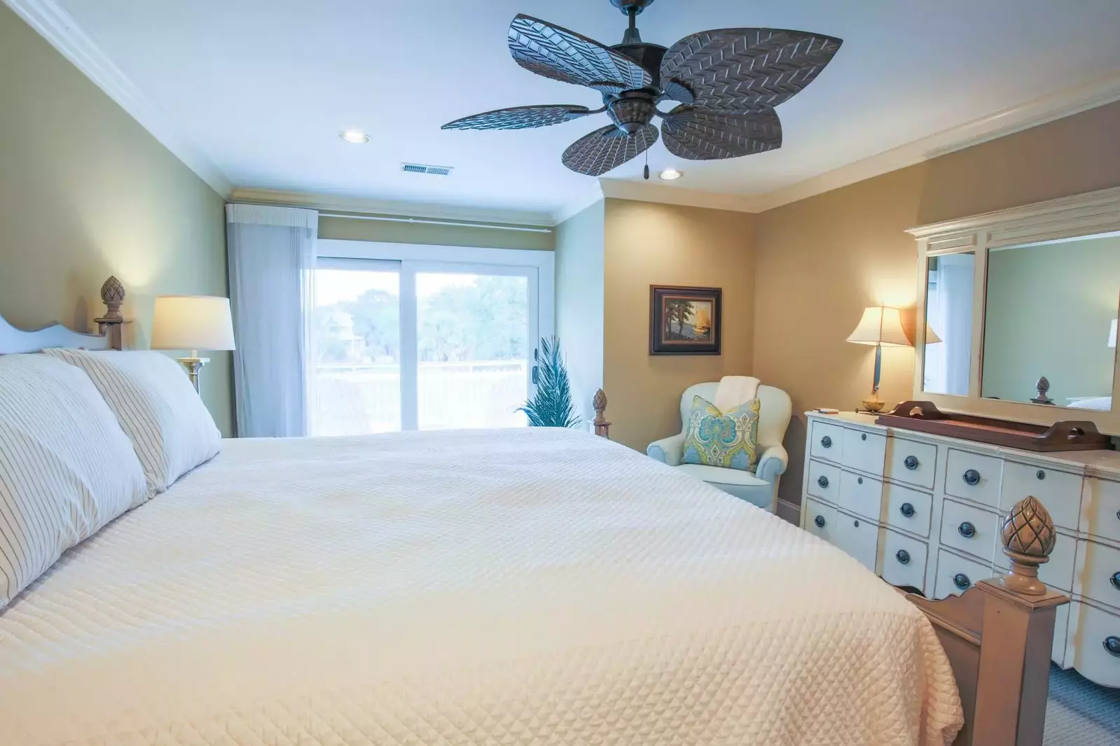 The master suite also features a dresser, arm chair and access to a private balcony.