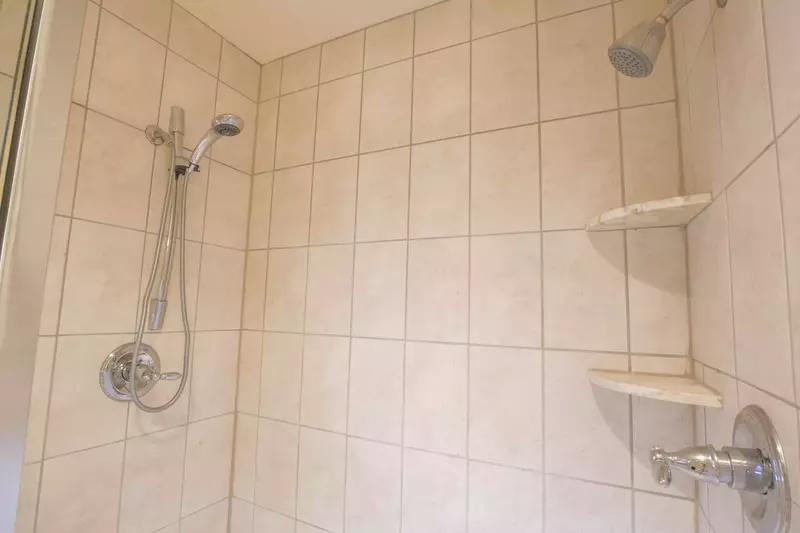 The master bathroom also has a tiled, walk-in shower with a separate handheld showerhead.