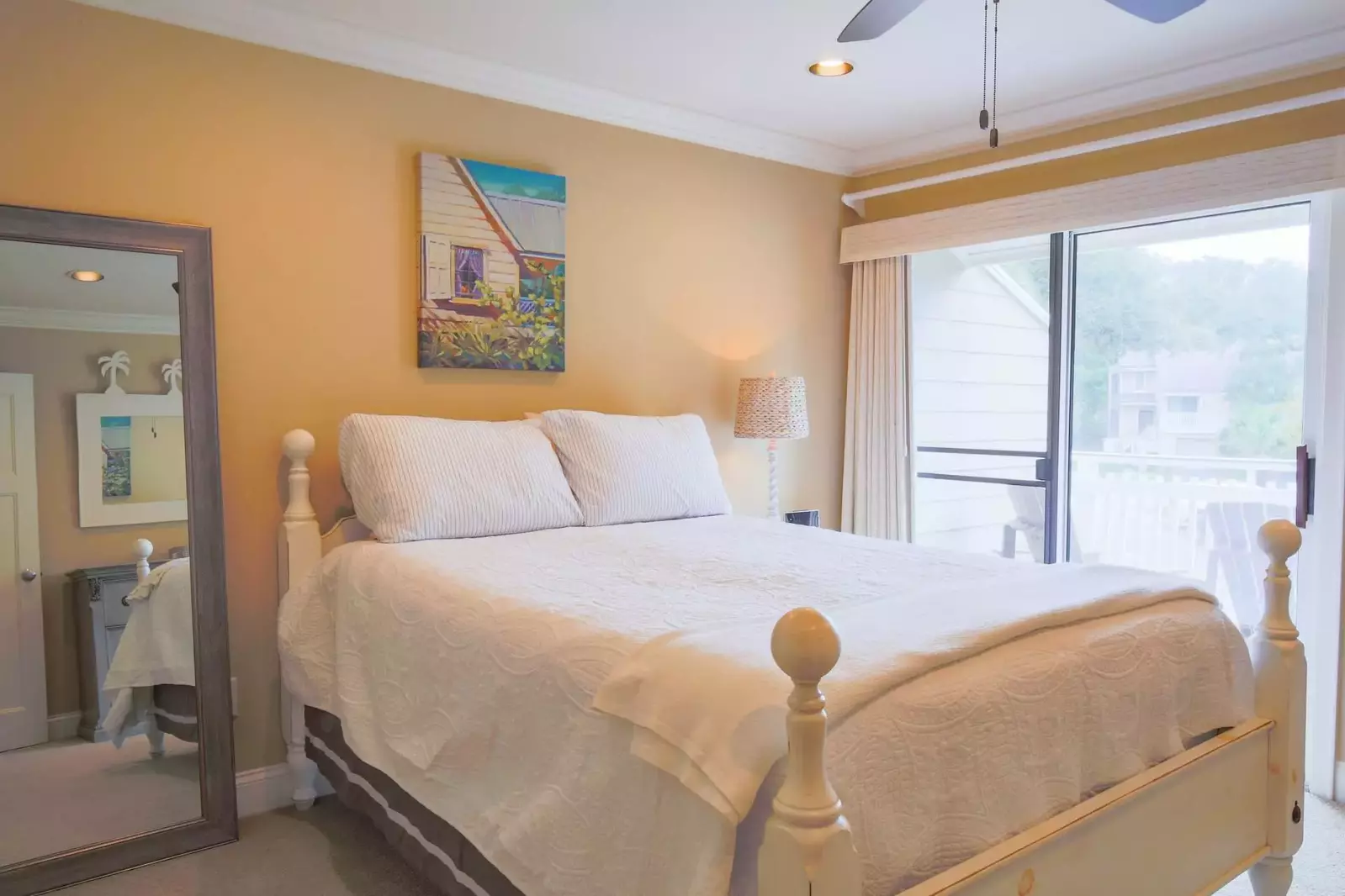 This guest bedroom features a queen bed, night stand with reading lamp and access to a private balcony.